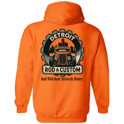 Back of an orange hoodie with a large round gear badge: "DETROIT" arched at top, an orange chopped hot rod coupe in front of a black Detroit skyline, a "ROD & CUSTOM" banner, and "Built With Heart Driven By History" in script below.