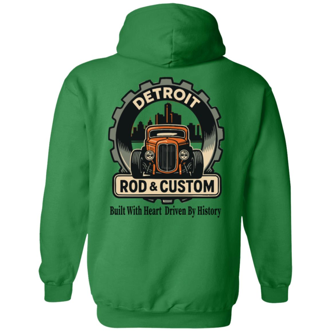 Back of a green hoodie with a large round gear badge: "DETROIT" arched at top, an orange chopped hot rod coupe in front of a black Detroit skyline, a "ROD & CUSTOM" banner, and "Built With Heart Driven By History" in script below.