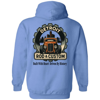 Back of a light blue hoodie with a large round gear badge: "DETROIT" arched at top, an orange chopped hot rod coupe in front of a black Detroit skyline, a "ROD & CUSTOM" banner, and "Built With Heart Driven By History" in script below.