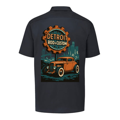 Back of a black Dickies short-sleeve work shirt with an orange Atomic Coupe hot rod under a DETROIT ROD & CUSTOM gear badge.