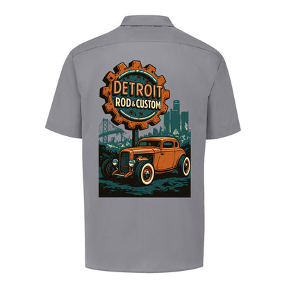 Back of a graphite grey Dickies short-sleeve work shirt with an orange Atomic Coupe hot rod under a DETROIT ROD & CUSTOM gear badge.