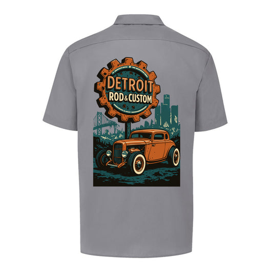 Back of a graphite grey Dickies short-sleeve work shirt with an orange Atomic Coupe hot rod under a DETROIT ROD & CUSTOM gear badge.