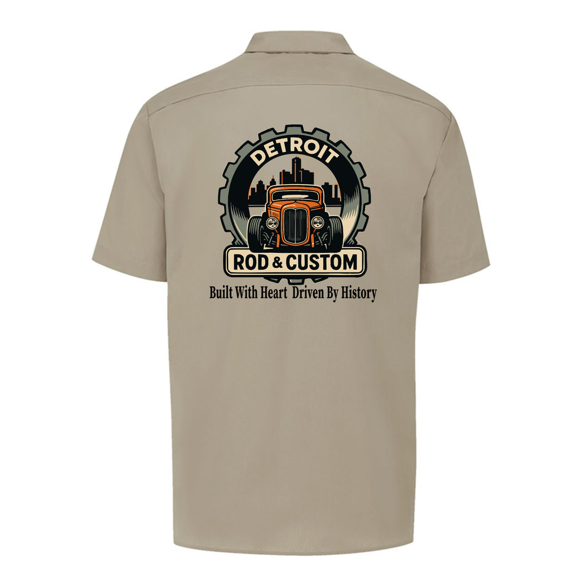 Back of a desert sand Dickies short-sleeve work shirt with an orange hot rod coupe in a DETROIT ROD & CUSTOM gear badge over the Detroit skyline, with Built With Heart Driven By History below.