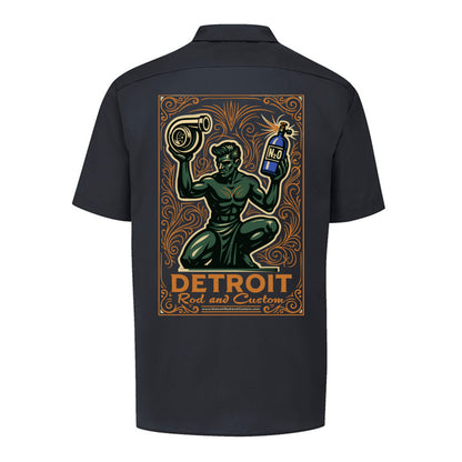 Back of a black Dickies work shirt with a large print of the green kneeling statue holding a turbo and a bottle, over an orange DETROIT Rod and Custom panel.