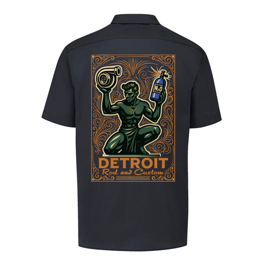 Back of a black Dickies work shirt with a large print of the green kneeling statue holding a turbo and a bottle, over an orange DETROIT Rod and Custom panel.