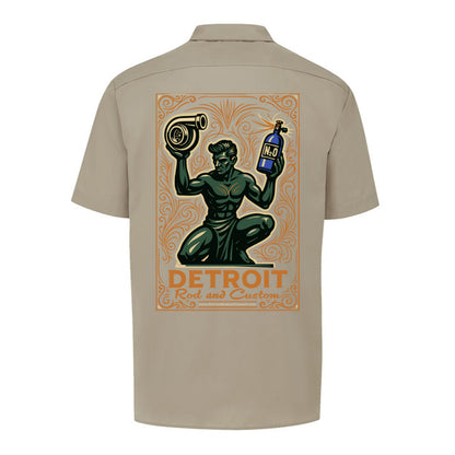 Back of a desert sand Dickies work shirt with a large print of the green kneeling statue holding a turbo and a bottle, over an orange DETROIT Rod and Custom panel.
