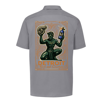 Back of a graphite grey Dickies work shirt with a large print of the green kneeling statue holding a turbo and a bottle, over an orange DETROIT Rod and Custom panel.