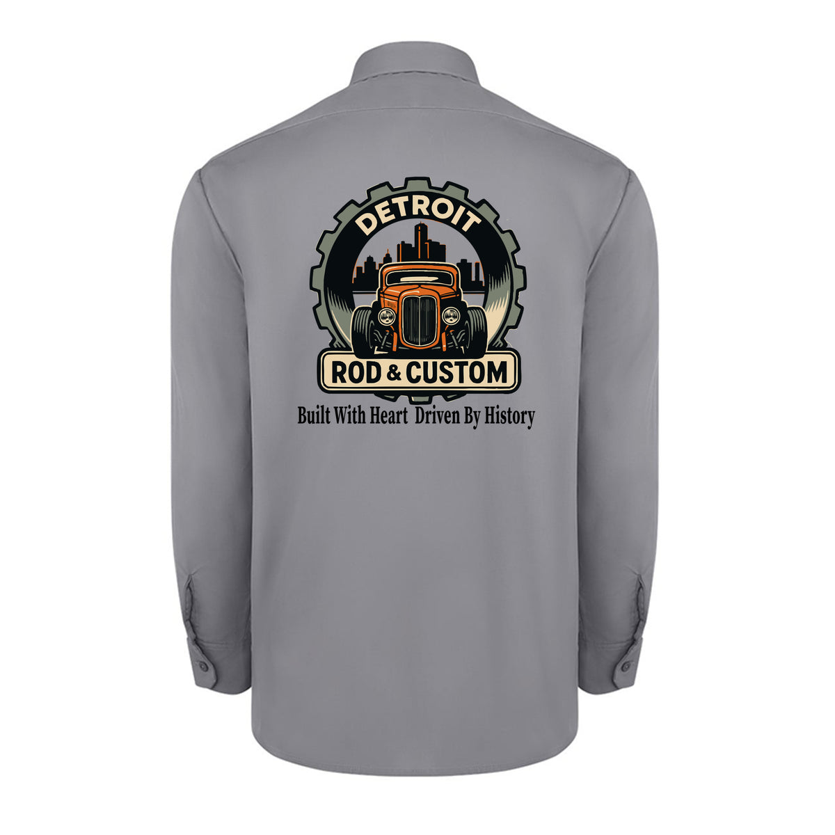 Back of a graphite grey Dickies long-sleeve work shirt with an orange hot rod coupe in a DETROIT ROD & CUSTOM gear badge over the Detroit skyline, with Built With Heart Driven By History below.
