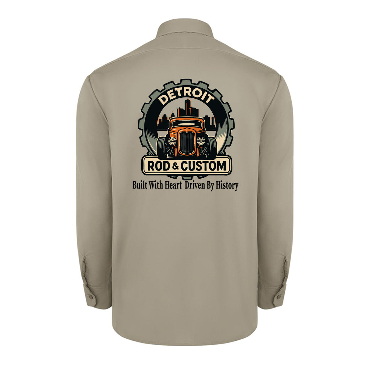 Back of a desert sand Dickies long-sleeve work shirt with an orange hot rod coupe in a DETROIT ROD & CUSTOM gear badge over the Detroit skyline, with Built With Heart Driven By History below.