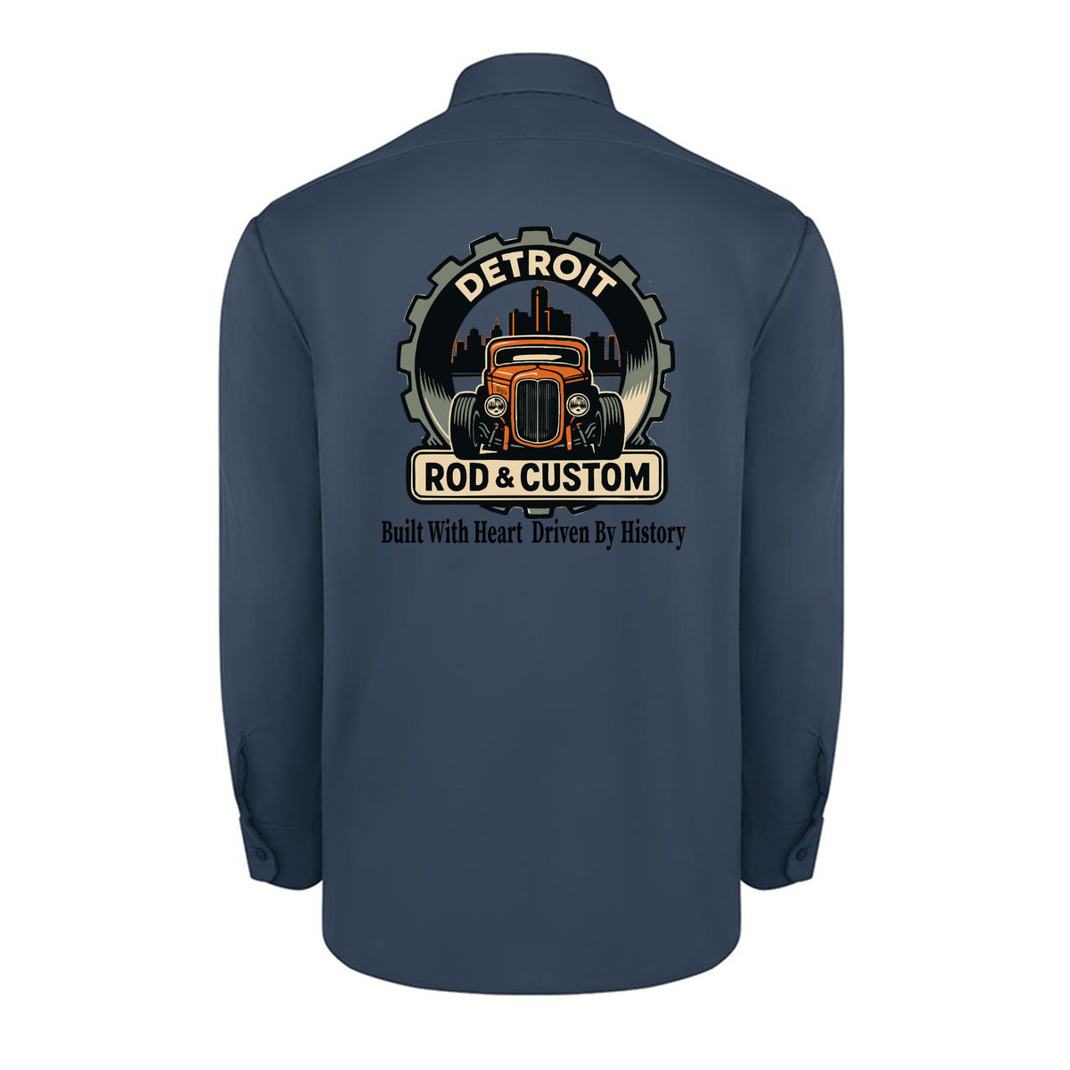 Back of a dark navy Dickies long-sleeve work shirt with an orange hot rod coupe in a DETROIT ROD & CUSTOM gear badge over the Detroit skyline, with Built With Heart Driven By History below.
